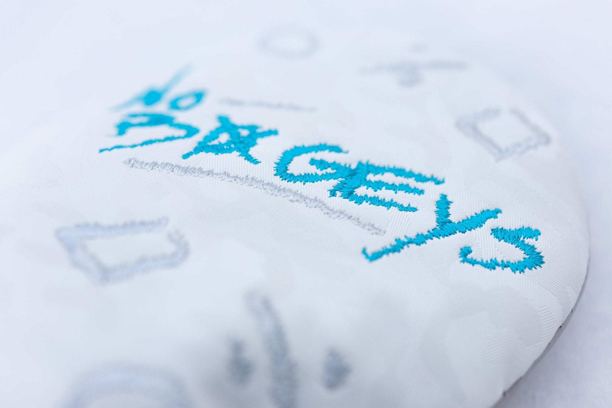 Close-up of embroidered blue and gray details on the No Bogeys White Fairway Cover golf headcover