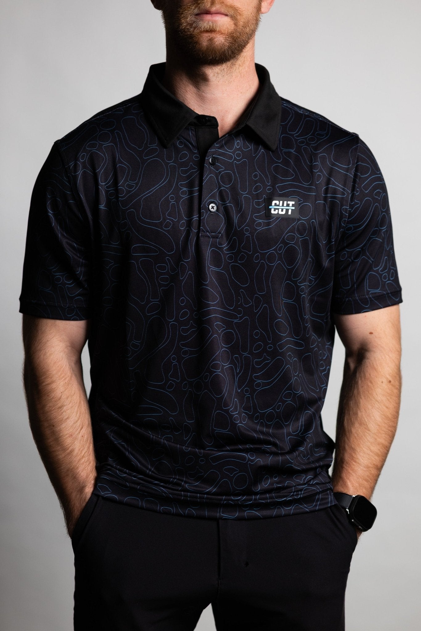 Man wearing a black Midnight Teal Topo Polo with subtle topographic patterns and a small Cutline Golf Goods logo on chest