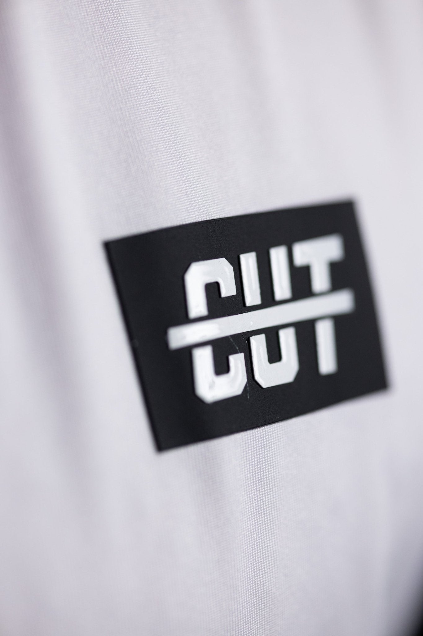 Close-up of a black and white logo patch on the GOLF Arm Whiteout Polo golf apparel fabric.