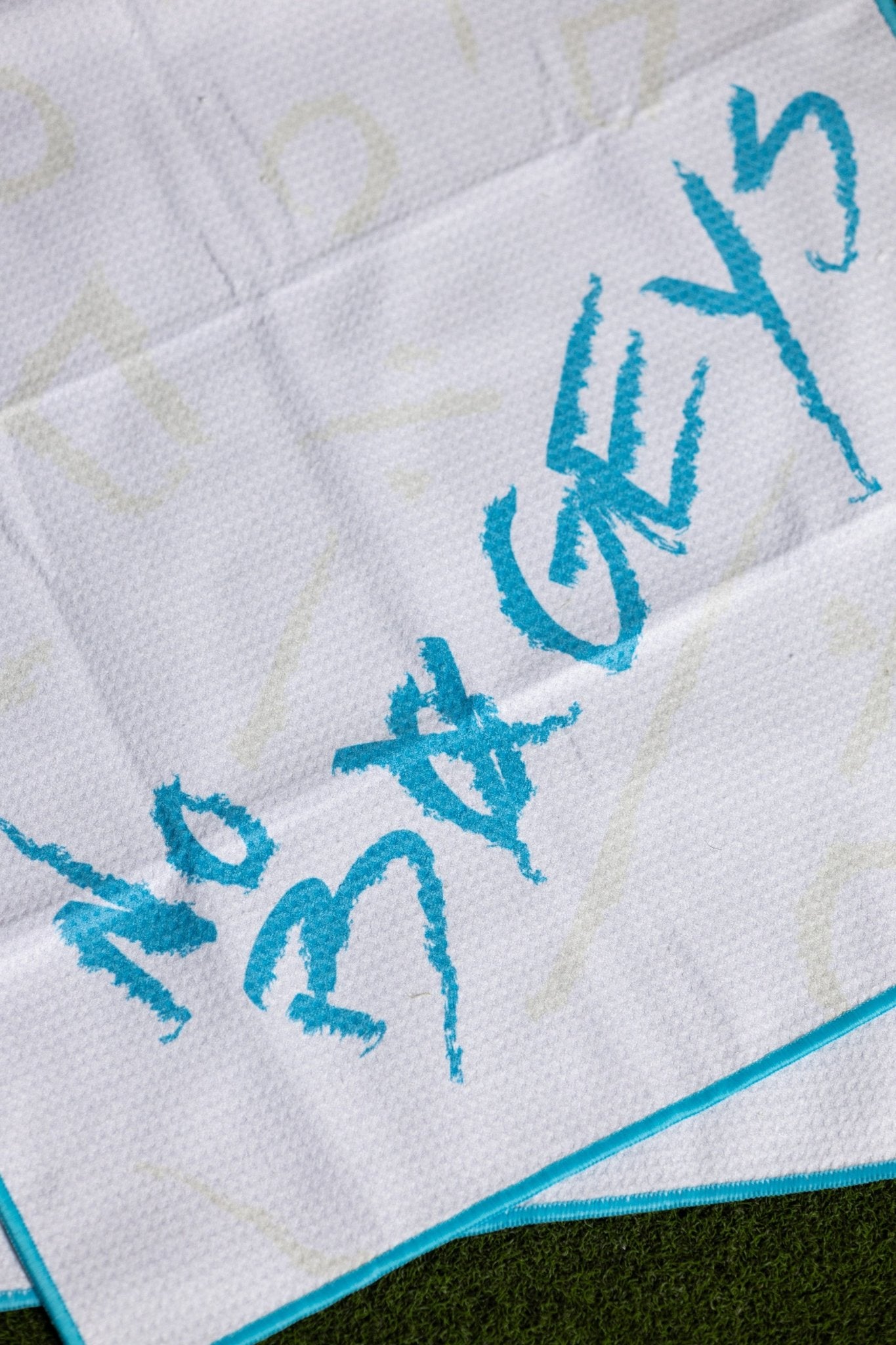 No Bogeys Oversized Towel with textured white fabric and bright blue lettering on grass background