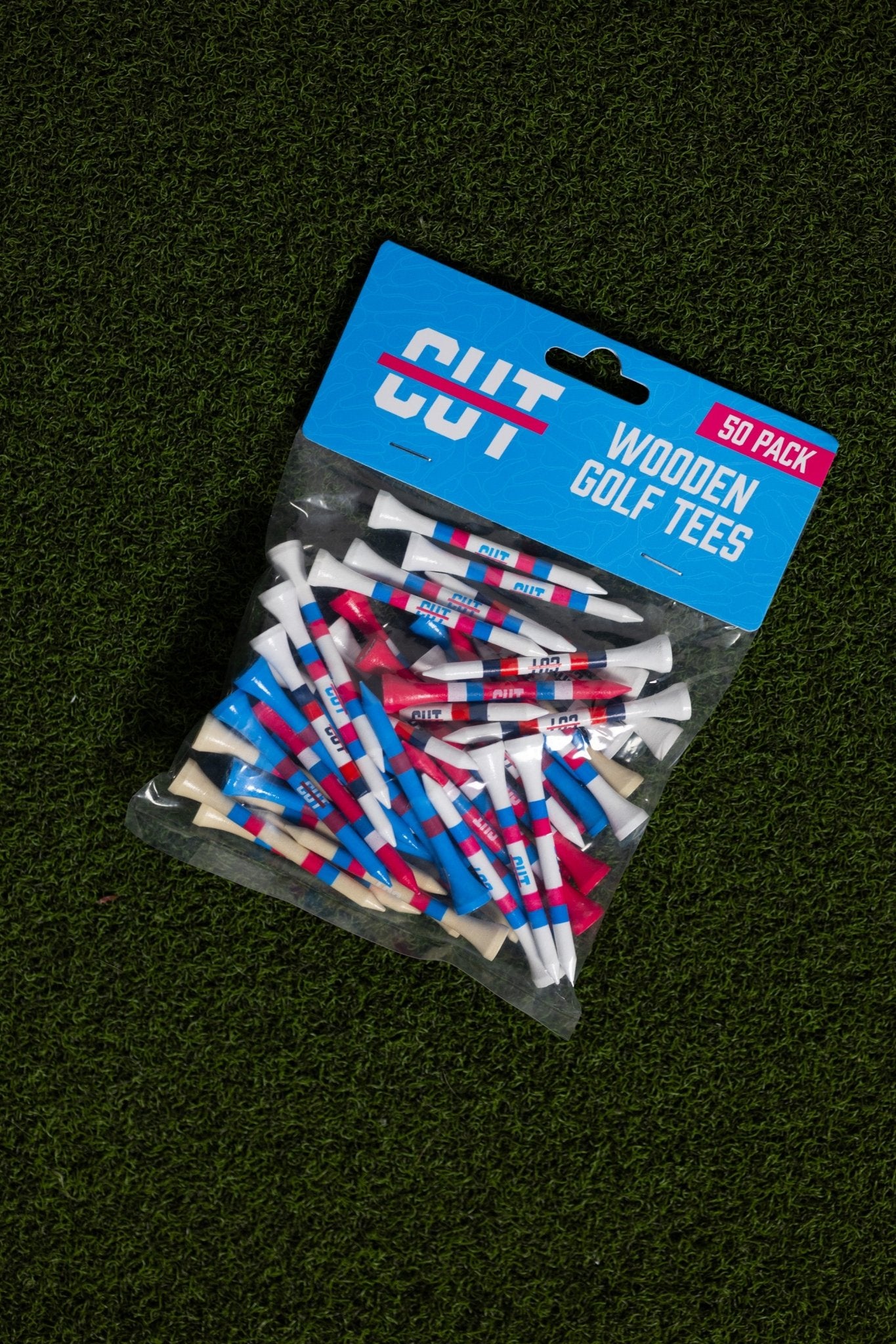 Multi Color 50 Pack Golf Tees in red, blue, white colors packaged in clear bag on green grass background
