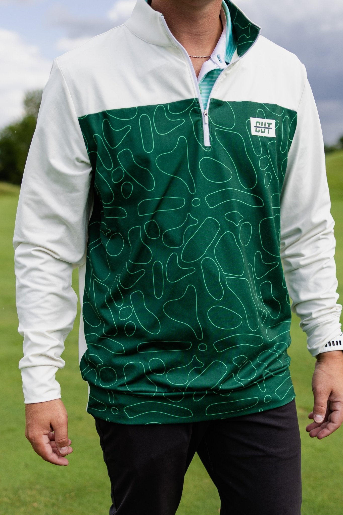 Man wearing a Green Topo Athletic Q-Zip with a green abstract pattern and white sleeves on a golf course