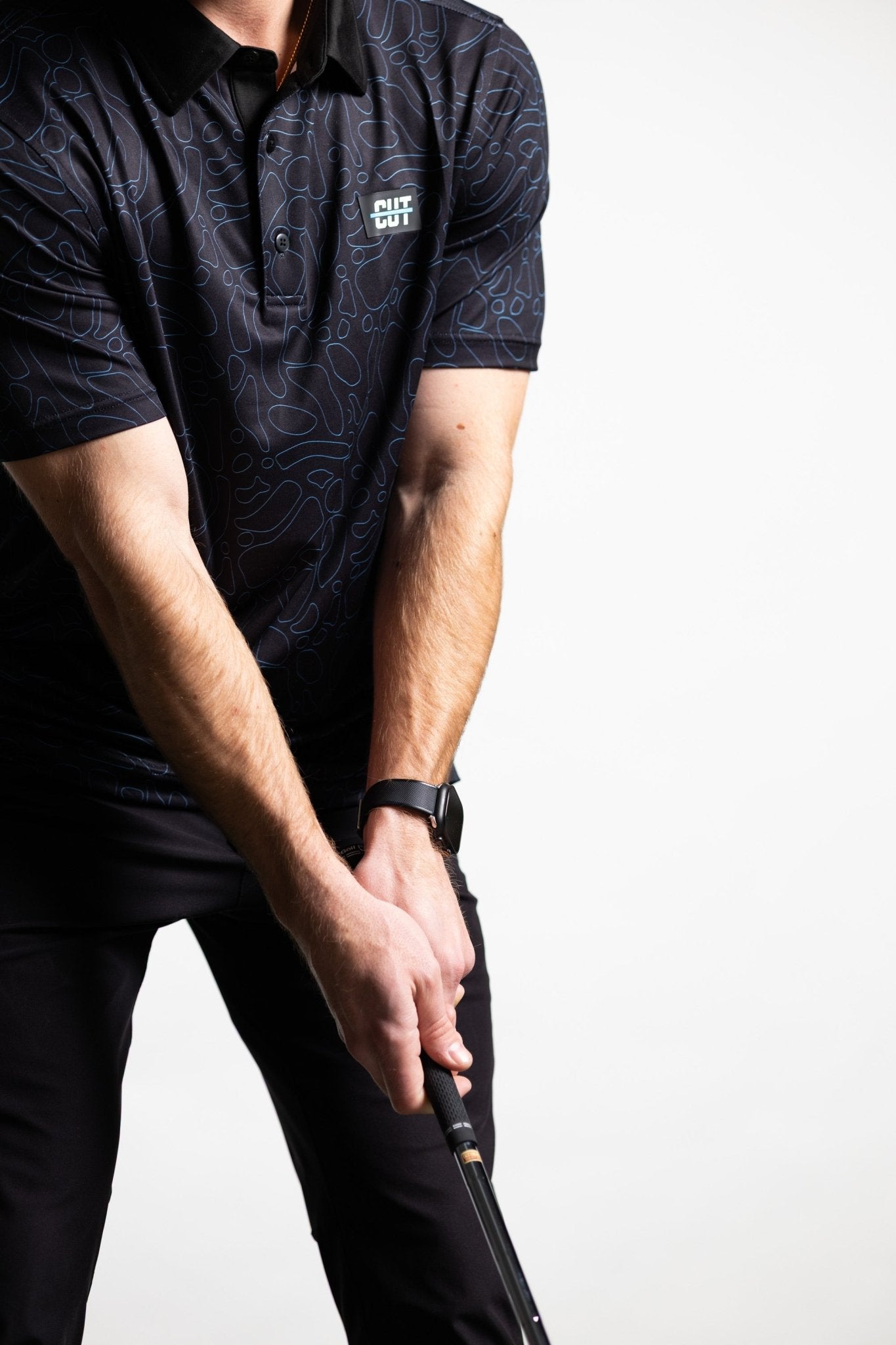 Man in a golf pose wearing a Midnight Teal Topo Polo with subtle teal contour patterns and black collar