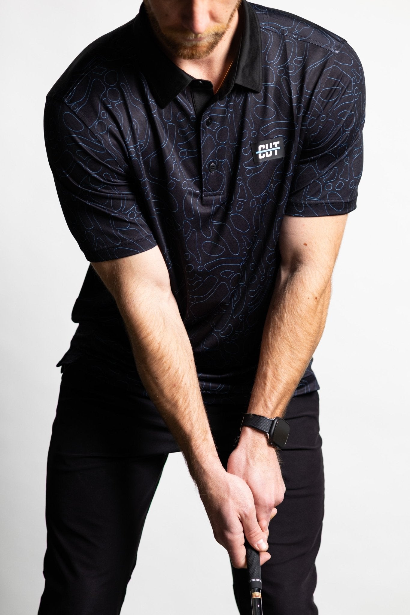 Man wearing a Midnight Teal Topo Polo golf shirt with topographic pattern preparing to swing golf club