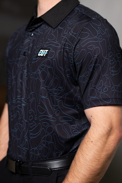 Close-up of a man wearing a Midnight Teal Topo Polo with an abstract pattern and a black collar in golf apparel style