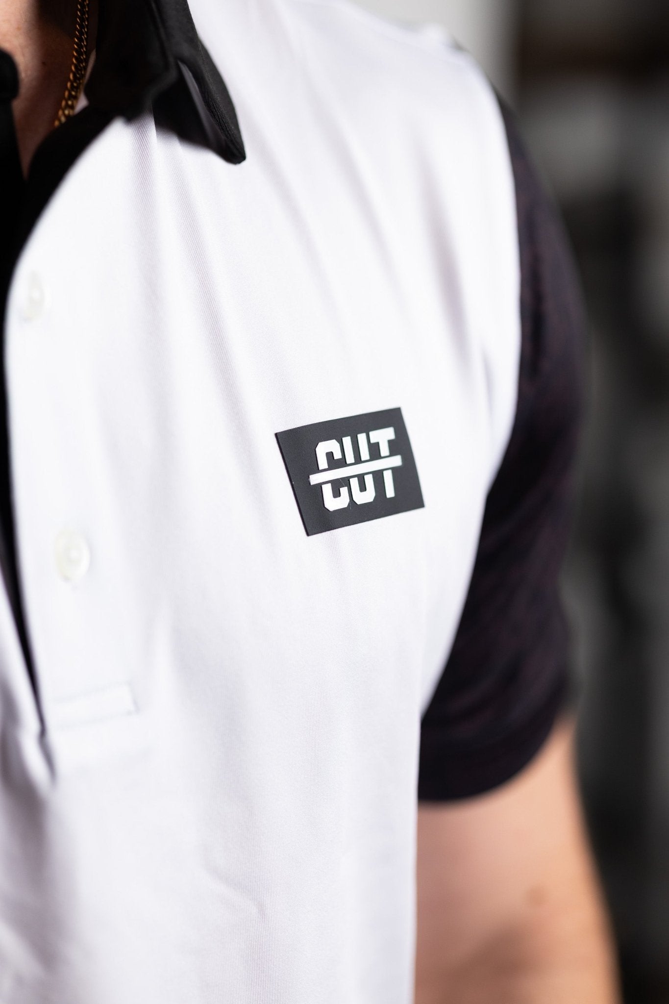 Close-up of a man wearing the GOLF Arm Whiteout Polo with a white front and black collar and sleeves, golf apparel style.