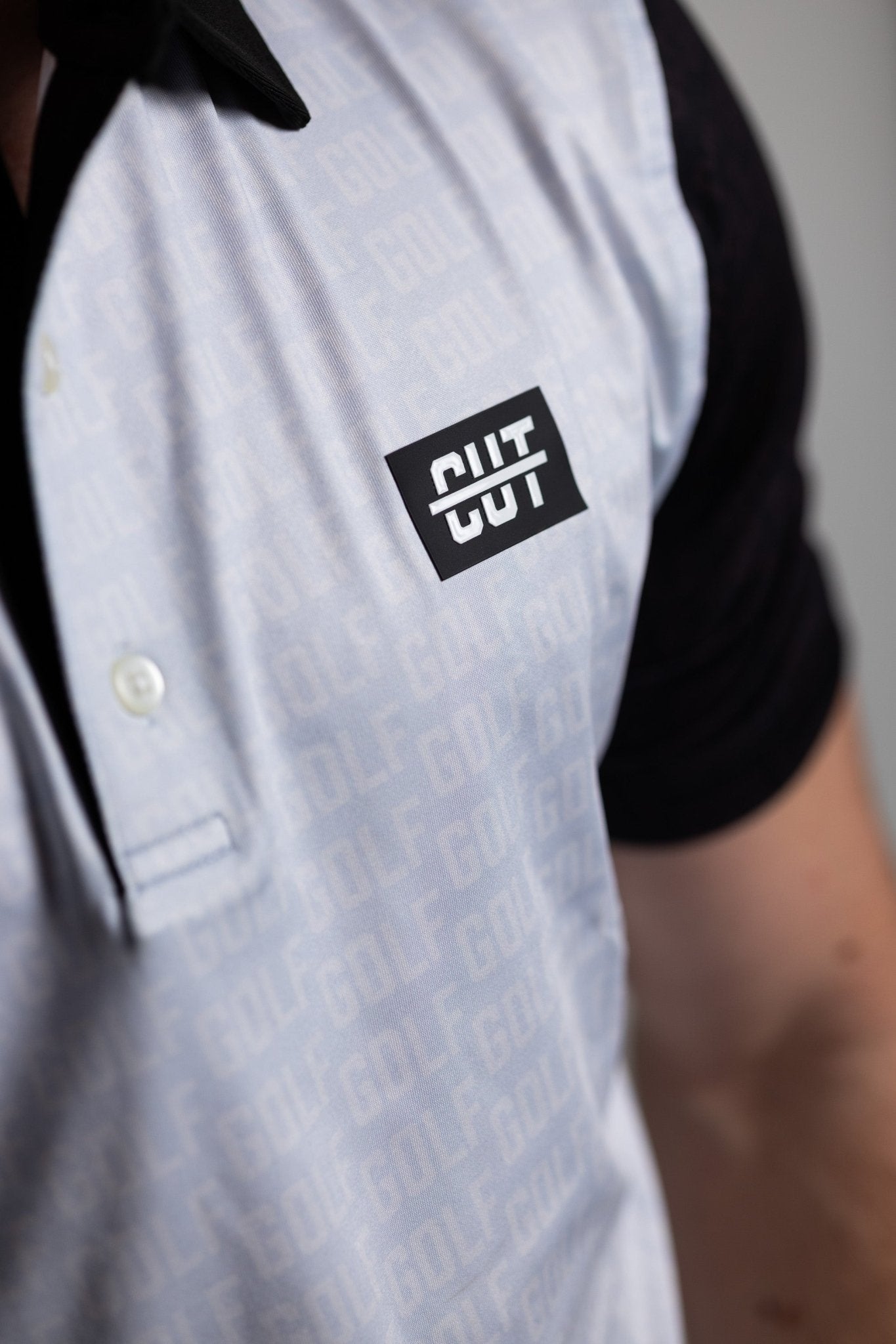 Close-up of a GOLF Pattern Off White Polo with subtle golf text pattern and contrasting dark collar and sleeves