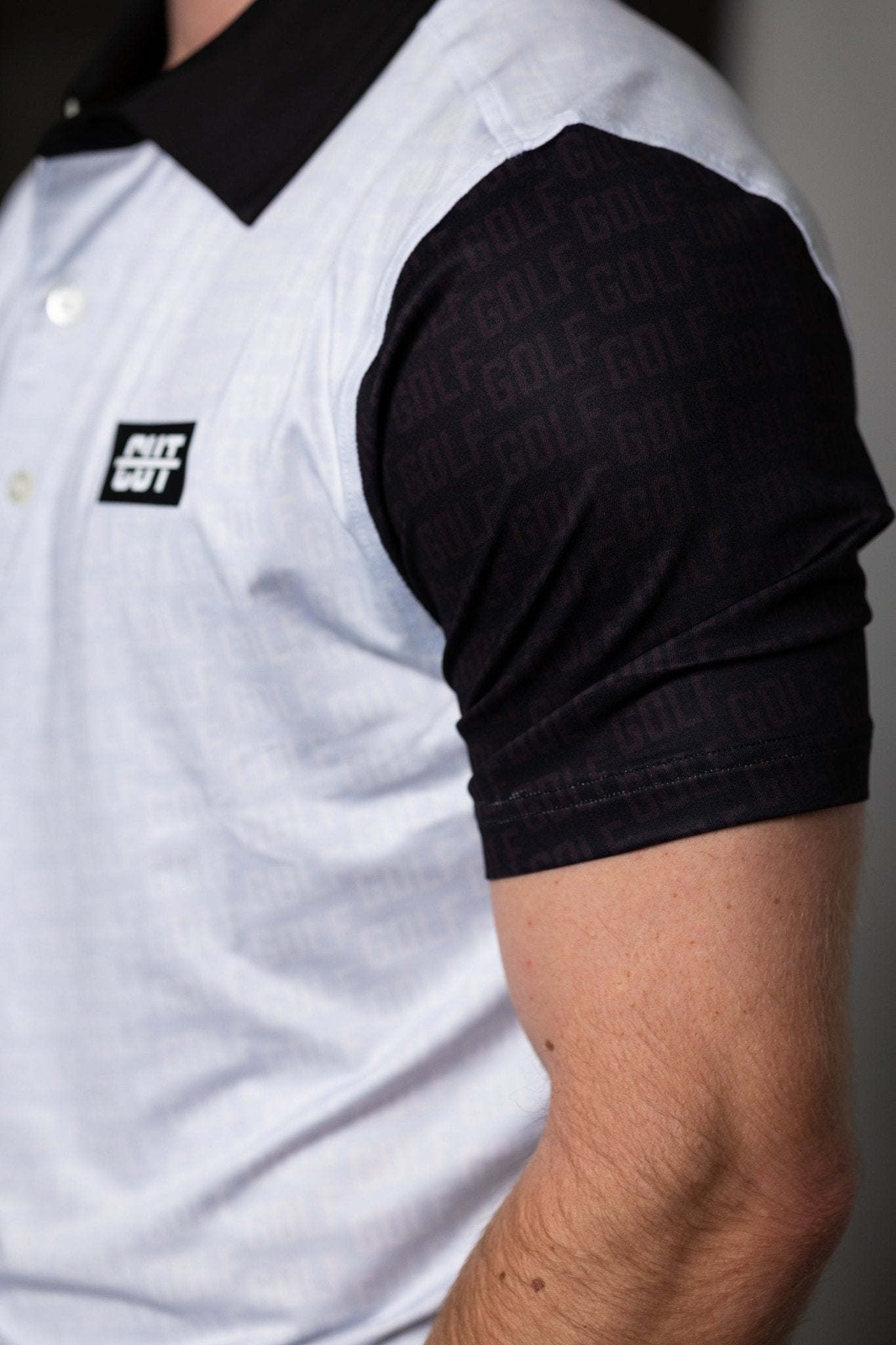 Close-up of a man wearing a GOLF Pattern Off White Polo with a black collar and patterned black sleeve.