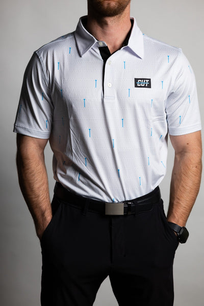 Man wearing a white golf polo shirt with blue tee patterns and black pants featuring the Teal "Tee" Polo logo