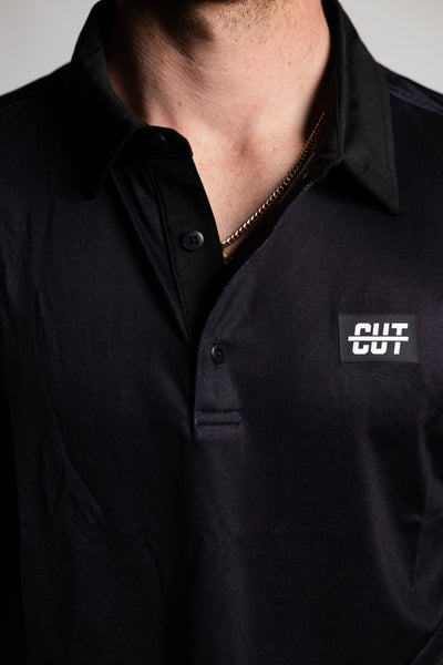 Close-up of a man wearing the Deep Topo Black Polo with a subtle pattern and a logo patch on the chest