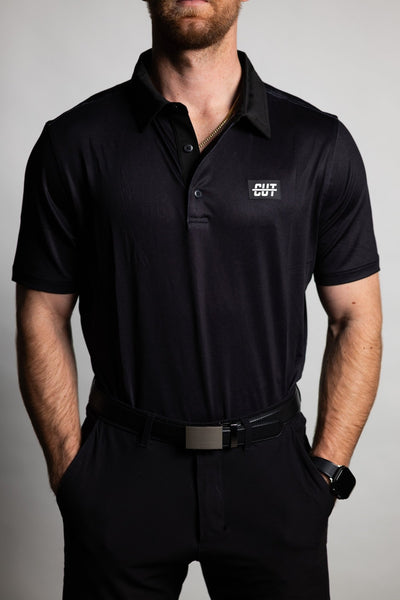 Man wearing a Deep Topo Black Polo with short sleeves and a small logo on the chest, styled for golf apparel.