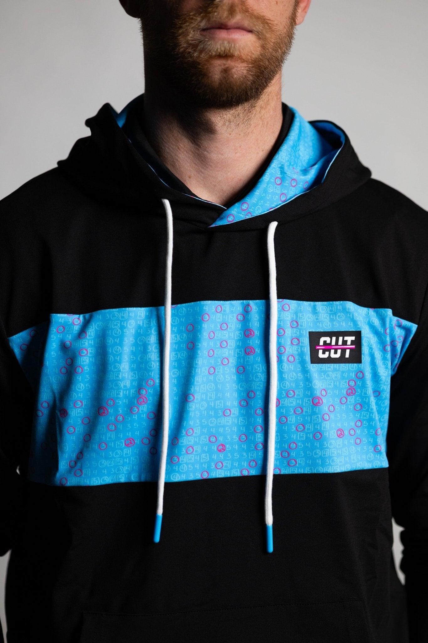 Man wearing a Teal Scorecard Athletic Hoodie with teal and black color blocking and white drawstrings