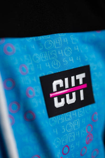 Close-up detail of teal patterned fabric with black patch and pink stripe on Teal Scorecard Athletic Hoodie