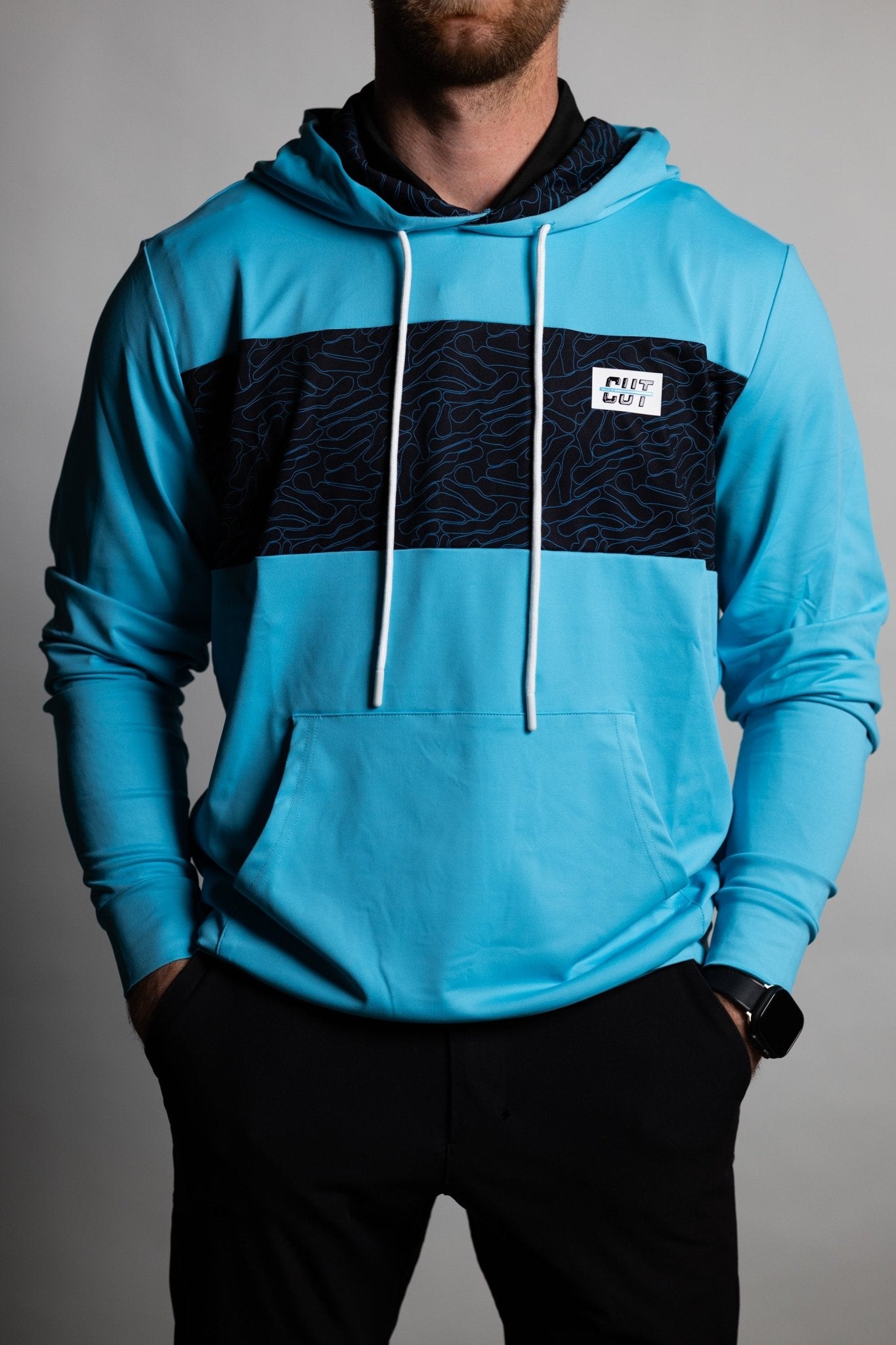 Man wearing a teal hoodie with black patterned chest panel and white drawstrings, featuring Teal Topo Athletic Hoodie.