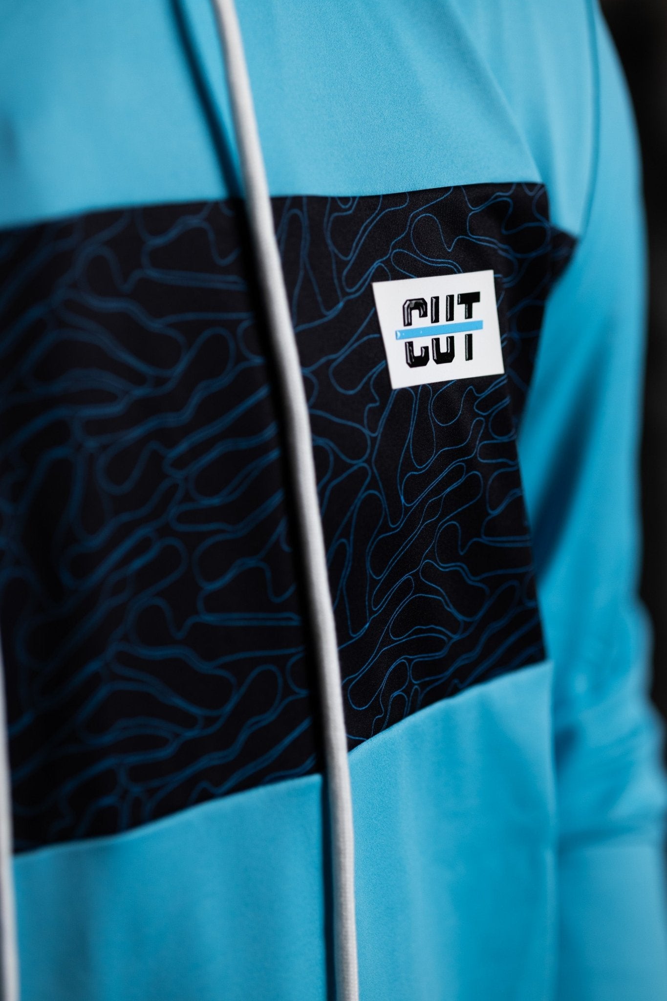 Close-up of the chest detail on a Teal Topo Athletic Hoodie with contour pattern and logo patch