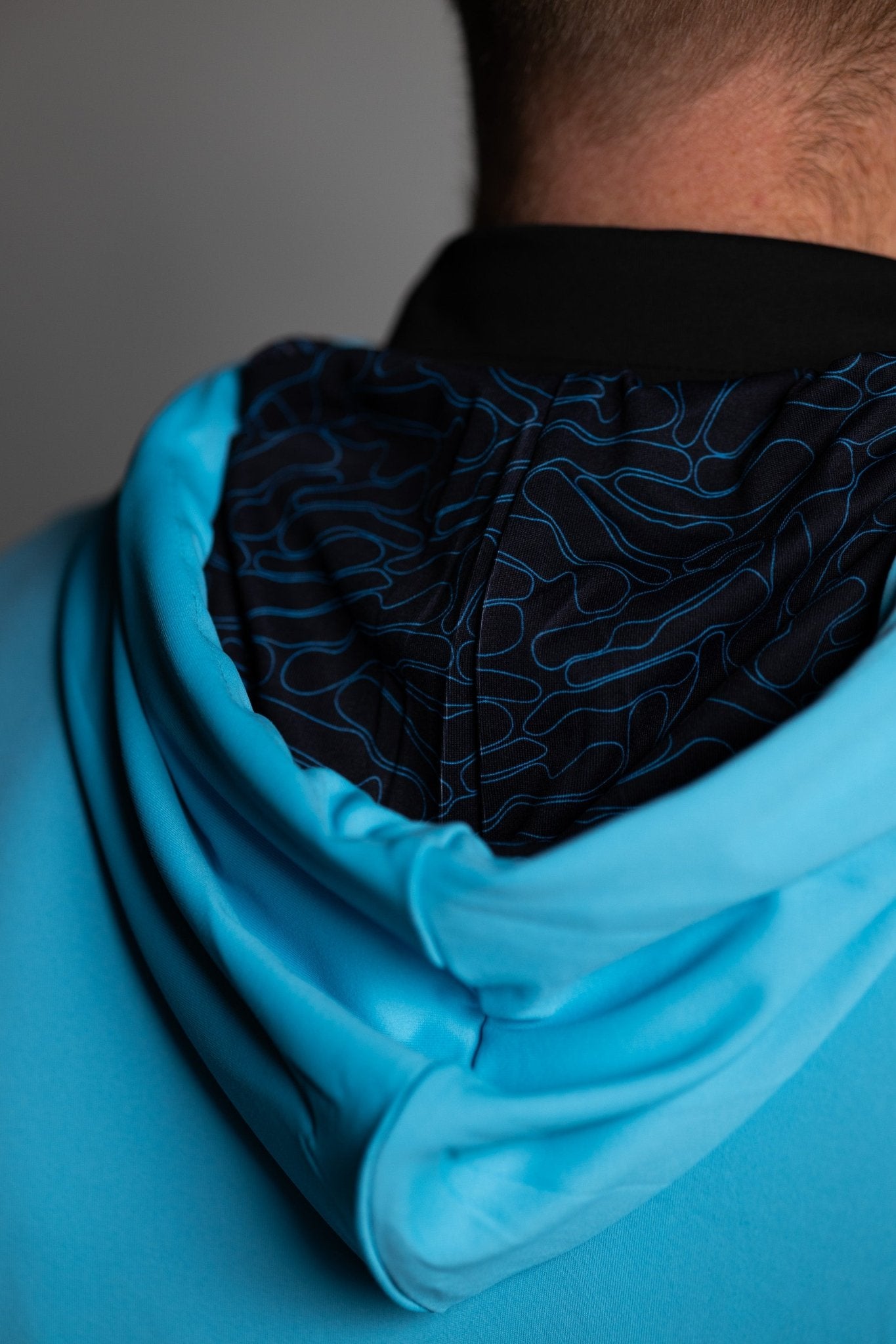 Close-up of the back hood lining showing a blue and black pattern on the Teal Topo Athletic Hoodie worn by a man