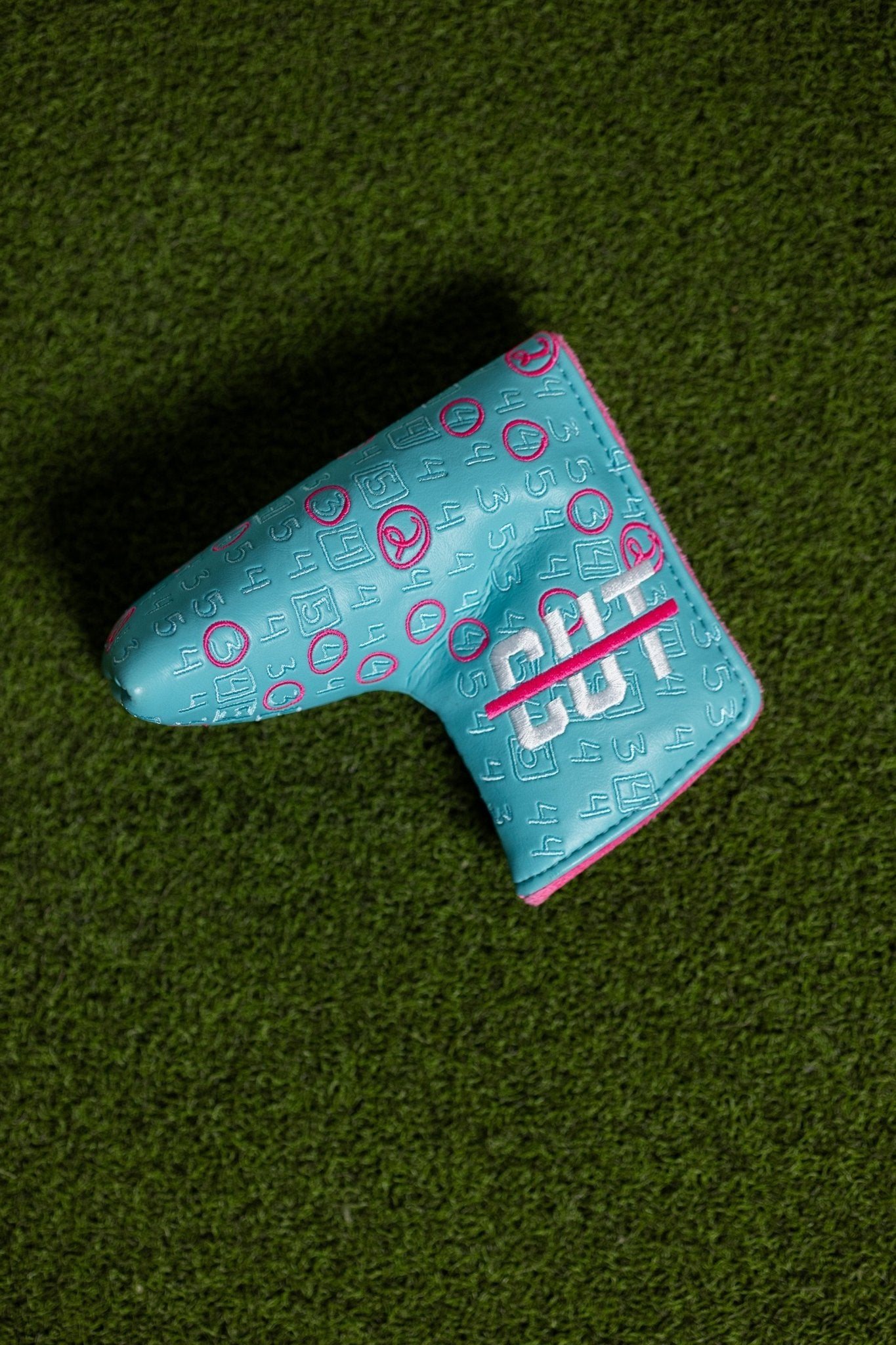 Scorecard Teal Blade golf putter cover with teal and pink design on green turf background