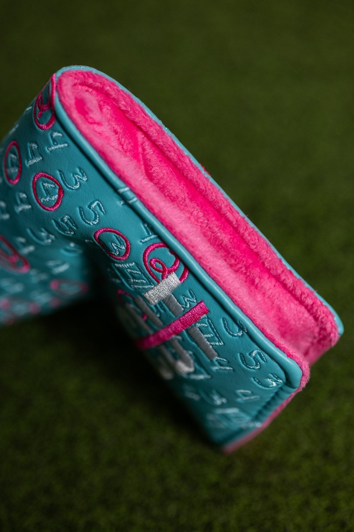 Scorecard Teal Blade golf headcover with teal exterior and soft bright pink interior lining on grass background