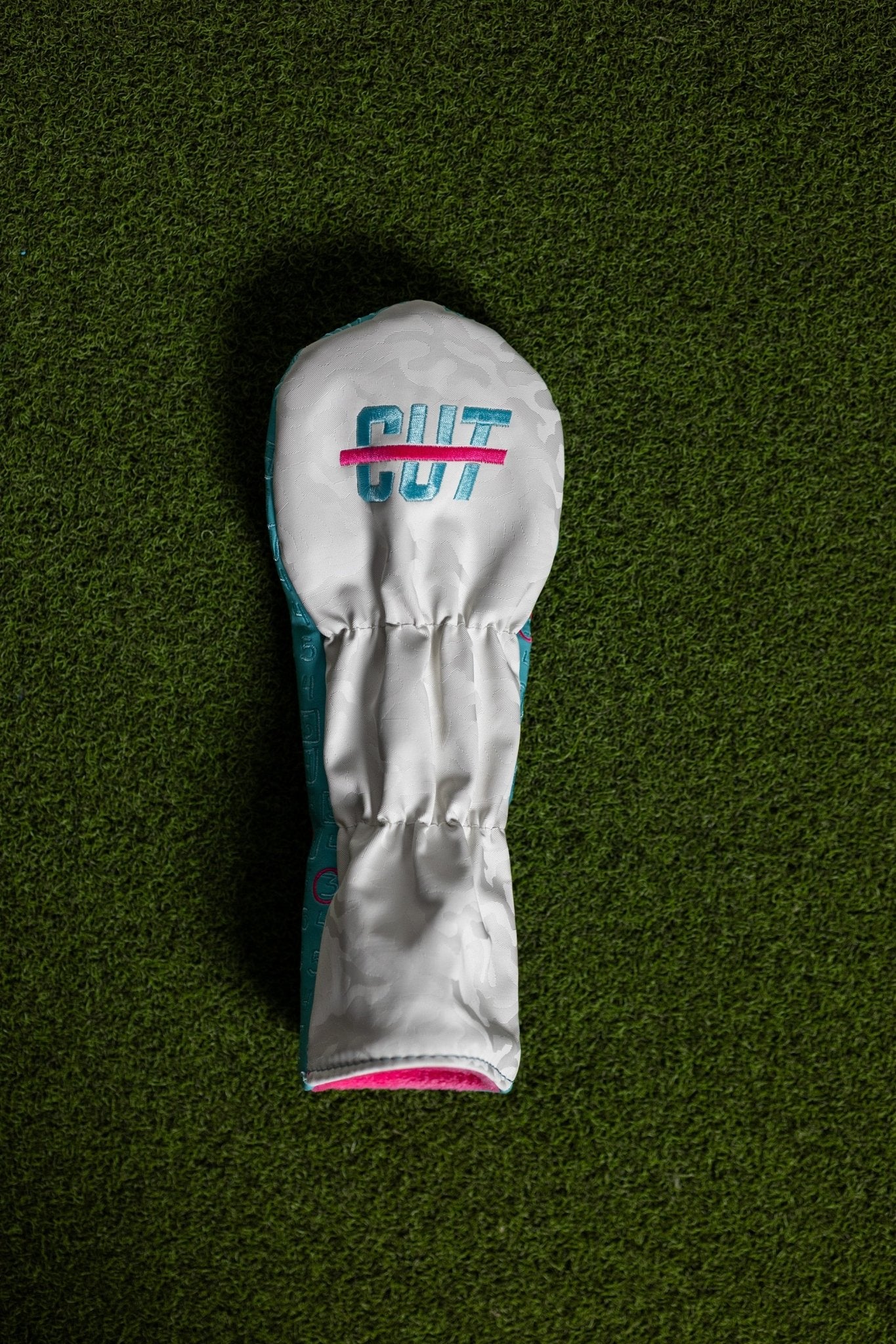 Scorecard Teal Fairway Cover with teal and white design and pink accents lying on green grass background
