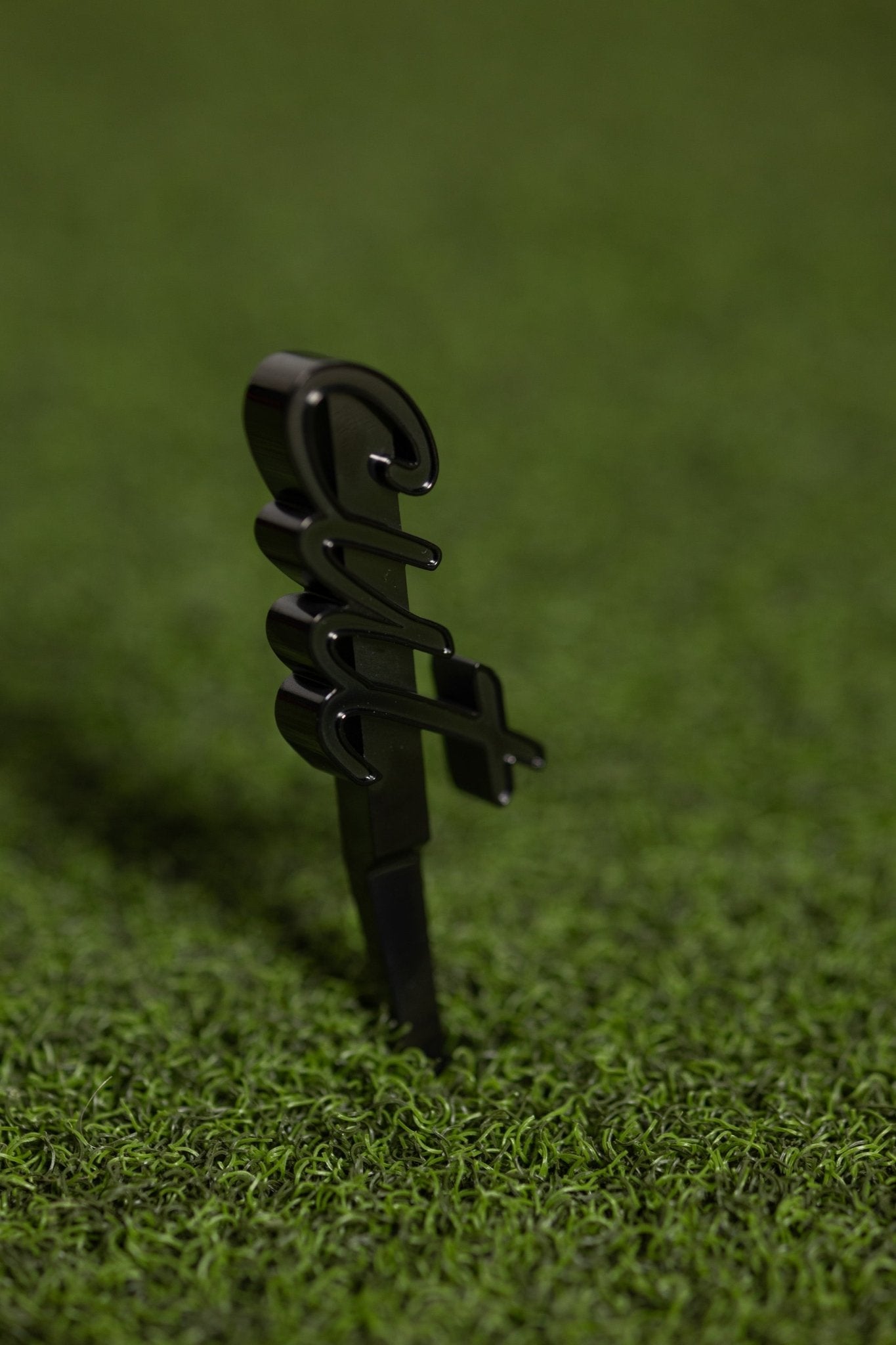CUT Script Black Divot Tool inserted in green turf, sleek black golf accessory for repairing divots on the course