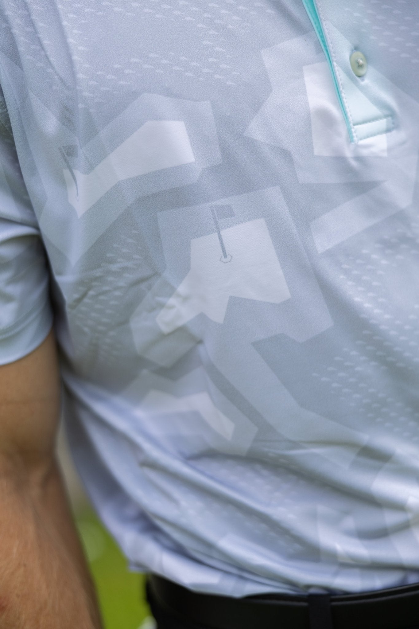 Close-up of a white and grey patterned Future Grey Pin Polo with subtle golf flag design on breathable fabric.