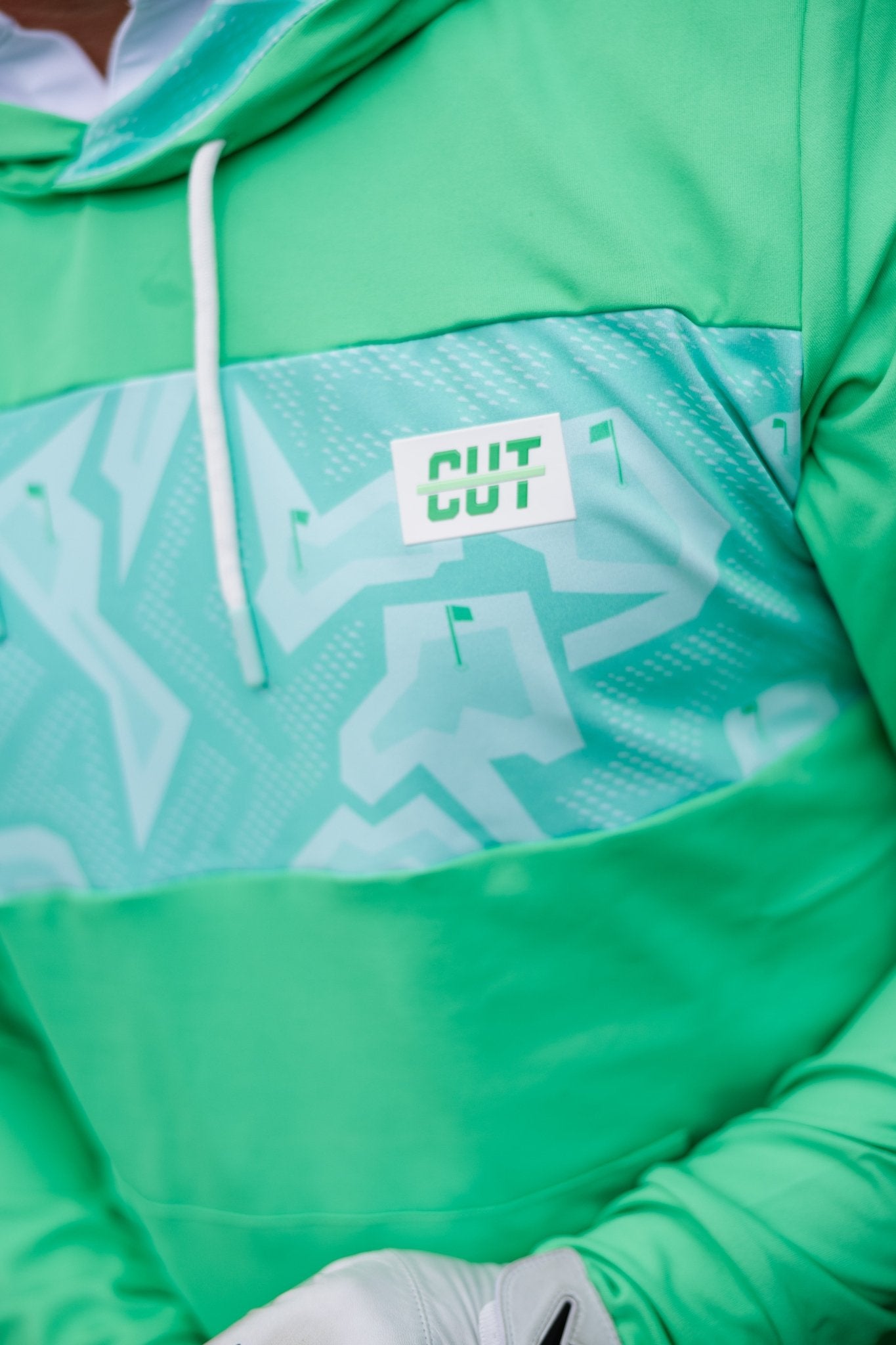 Close-up of a green Mint Future Tech Athletic Hoodie with abstract pattern and drawstring detail on chest area