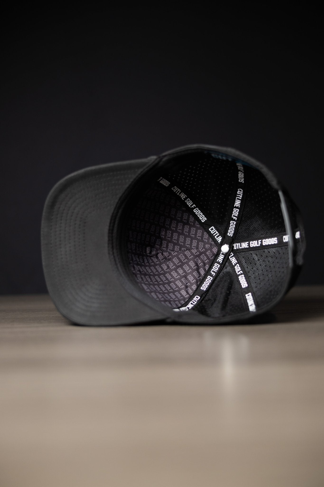 Inside view of a black Blackout Cutline Hat showing Cutline Golf Goods branded lining and black mesh panels