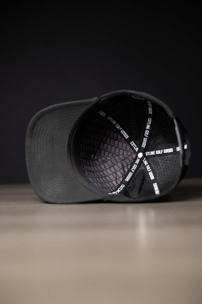 Inside view of a black Blackout Cutline Hat showing Cutline Golf Goods branded lining and black mesh panels