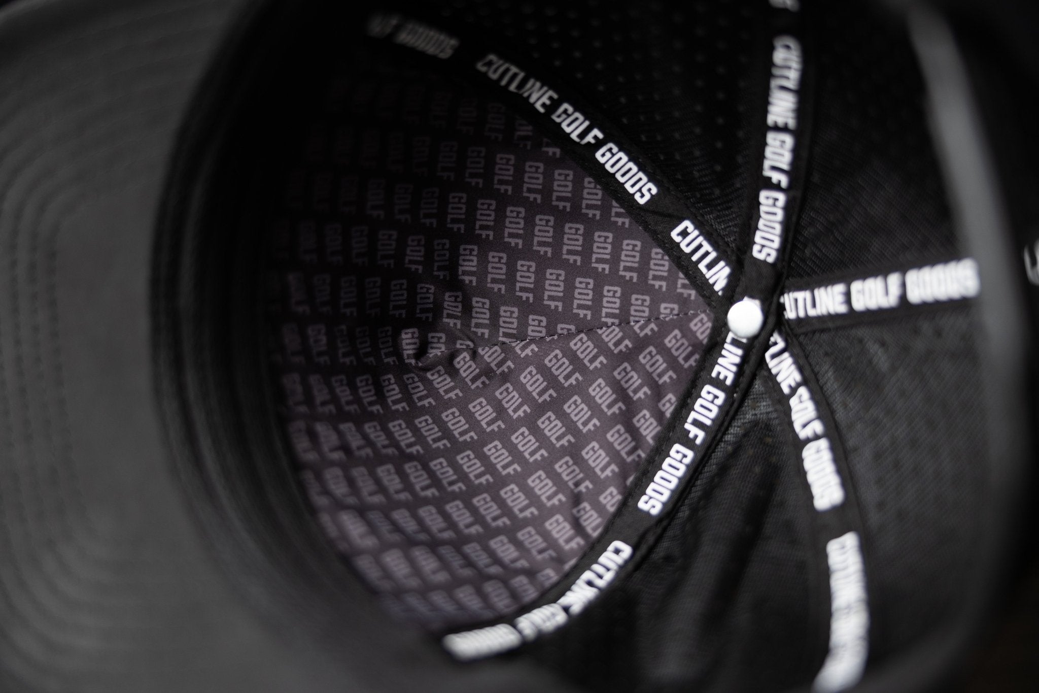 Inside view of Blackout Cutline Hat showing branded inner lining and stitching details in black golf gear style