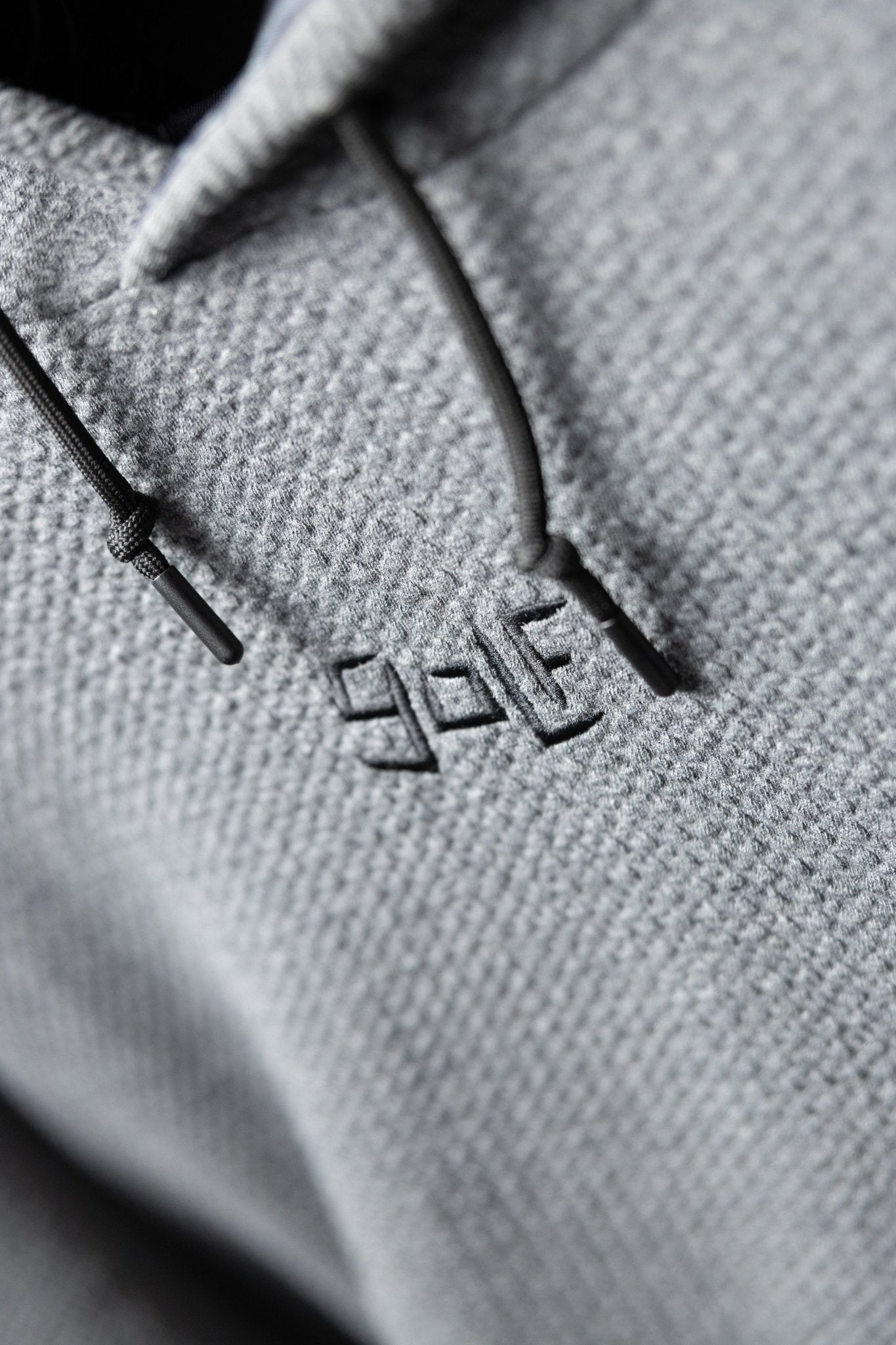 Close-up of waffle knit texture and embroidered logo on the Waffle Knit Cobalt Grey GOLF Hoodie with drawstrings visible