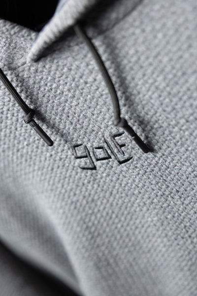 Close-up of waffle knit texture and embroidered logo on the Waffle Knit Cobalt Grey GOLF Hoodie with drawstrings visible