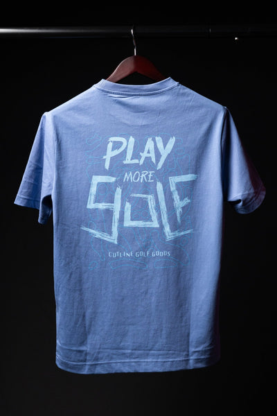 Light blue Play More Golf T-Shirt with graphic text hanging on dark wooden hanger against black background