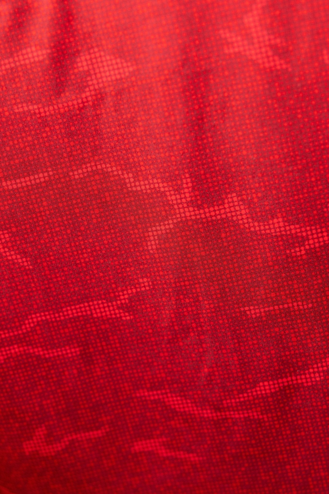 Close-up texture of True Red Tech Camo Polo fabric showcasing red digital camo pattern for golf apparel.